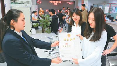 河北省承德市網(wǎng)絡(luò)代購經(jīng)營者陳晨(右)從工作人員手中接過帶有統(tǒng)一社會信用代碼的營業(yè)執(zhí)照。 劉環(huán)宇攝(人民圖片)