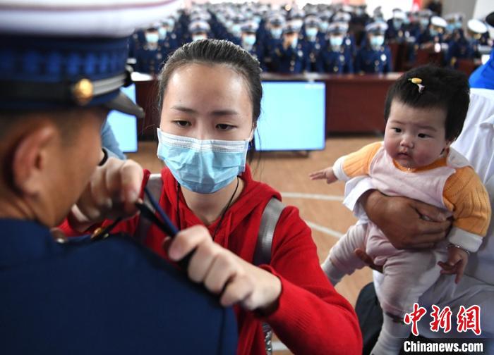 新消防員楊振的妻子彭莉與女兒現(xiàn)場見證丈夫加入“火焰藍(lán)”的神圣時(shí)刻。　劉忠俊 攝
